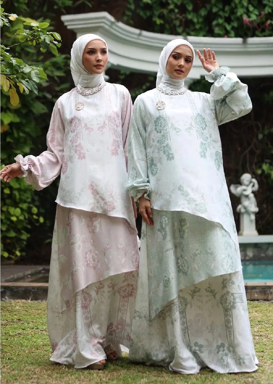 Dua model mengenakan setelan pastel bermotif floral di taman